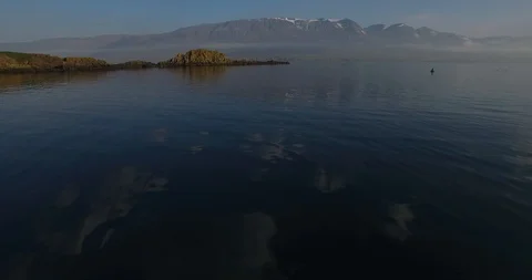 Slowly flying over clear ocean water with mountains in the back 스톡 동영상 105215298