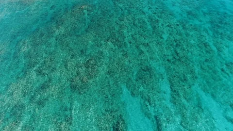 Slowly flying over teal colored water with the bottom visible through Video stock 109455042