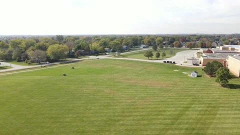 Slowly flying over of various school/community fields in a lawn mowing process Stock Footage 142489304