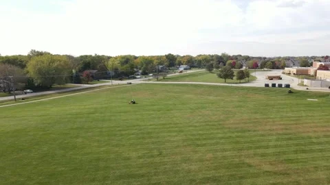 Slowly flying over of various school/community fields in a lawn mowing process Stock Footage 142489476