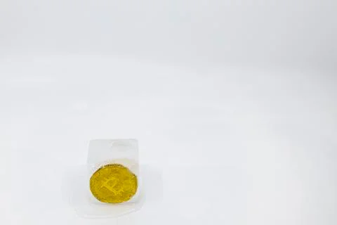 Slowly melting ice cube with a bitcoin token frozen in it on white background Foto stock