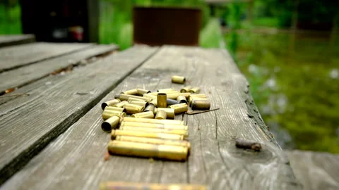 Slowly moving camera backward close up of empty bullet shells on wood table Stock Footage 311485414
