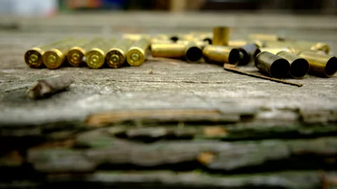 Slowly moving camera up revealing empty bullet shells laying on old wooden table Stock Footage 311485542