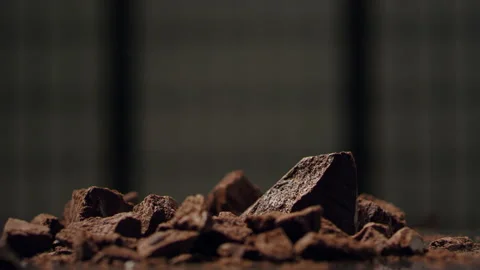 Slowly moving dark pieces of chocolate falling into a table  SLOW MOTION 4k Stock Footage 134949196