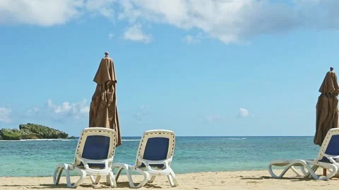 Slowly panorama on empty sandy ocean shore with beach chairs and closed Stock Footage 130746000