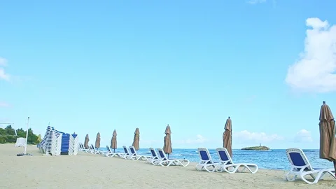 Slowly panorama at empty sandy seashore with beach chairs and closed umbrellas Video stock 128756665