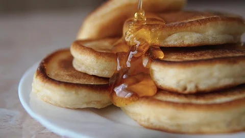 Slowly pouring honey jam on a stack of pancakes in a plate close-up 스톡 동영상 128963550