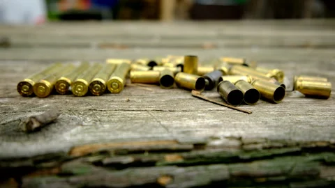 Slowly rising camera up revealing empty bullet shells laying on old wooden table Stock Footage 311485687
