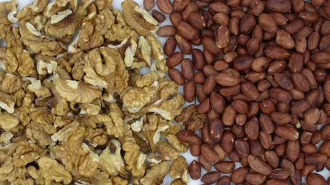 Slowly rotating walnuts and peanuts on a plate, top view Stock Footage 154047295