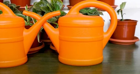 Slowly sliding from right to left along two orange garden watering cans Stock Footage 122340824