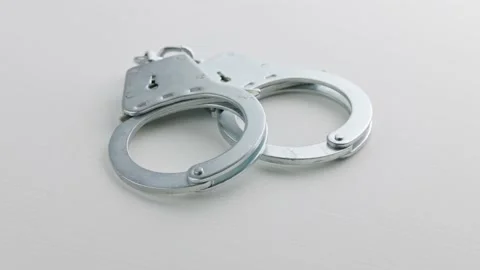 Slowly spinning silver handcuffs on white background Stock Footage 175978511