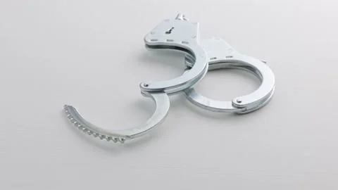 Slowly spinning silver handcuffs on white background Stock Footage 176217945