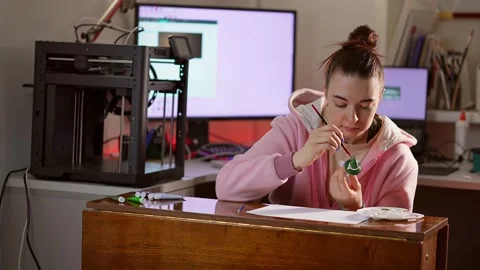 Slowmo of cheerful lady sitting in workshop near three dimensional printer and Stock Footage 314289909