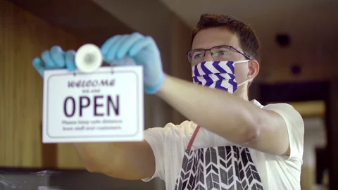 Slowmo Handsome Caucasian Worker In A Face Mask Turning Over Closed To Open Sign Stock Footage 140322904