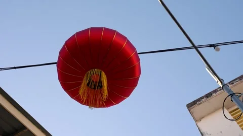 Slowmo red lantern suspended above street between buildings Vídeo Stock 333043081
