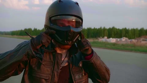 Slowmo tracking of man putting motorcycle helmet on outdoors Stock Footage 154916262
