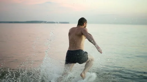 Slowmotion 200FPS. Caucasian guy dive into the water at sunset in the evening. Stock Footage 67392252