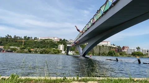 Slowmotion backflip from bridge under amazing blue sky Video stock 137970968