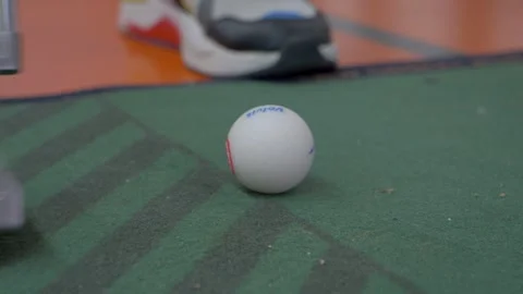 Slowmotion closeup shot of a golf ball being hit in a game of minigolf Stock Footage 249040441