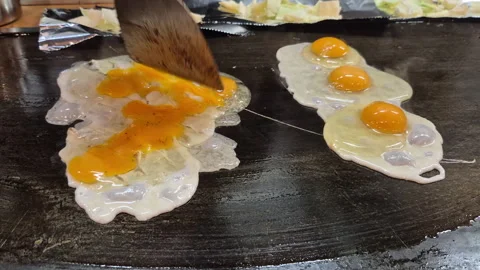 Slowmotion cooking eggs on teppan iron plate osaka okonomiyaki shop in Japan Stock Footage 329672326