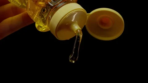 Slowmotion drizzle of honey out of a container Stockbeeldmateriaal 332678205
