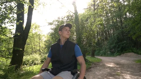 Slowmotion follow of disabled young student man in a wheelchair observing nature Stock Footage