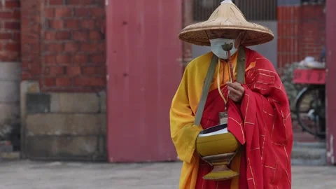 Slowmotion monk walking and chanting in colorful robe with temple columns behind Stock Footage 313628192