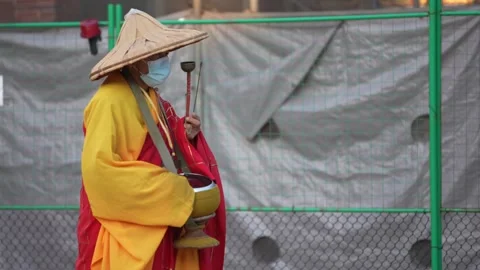 Slowmotion of monk walking in temple holding ritual bell and offering bowl Stock Footage 315059868