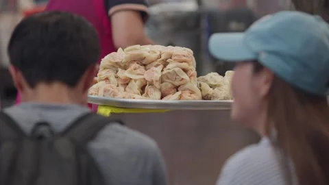 Slowmotion of seated tourists eating dumplings at Korean street food stall Seoul Stock Footage 314519341