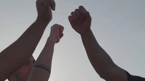 Slowmotion shot of three guys bump fisting each other to celebrate victory Stock Footage 208725967