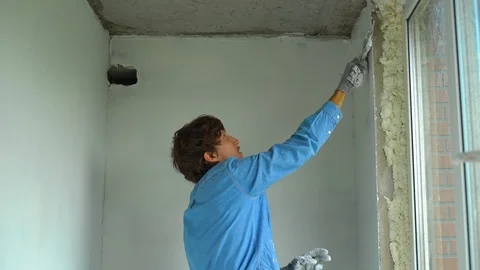 Slowmotion shot of a young painter applying putty on the walls Stock Footage 95489132