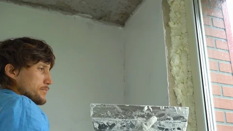 Slowmotion shot of a young painter applying putty on the walls Stock Footage 95489398