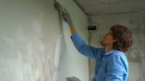 Slowmotion shot of a young painter applying putty on the walls Stock Footage 95489616