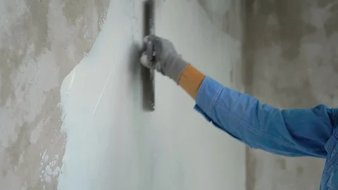Slowmotion shot of a young painter applying putty on the walls Stock Footage 95490203