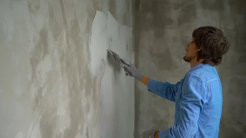 Slowmotion shot of a young painter applying putty on the walls Stock Footage 95490716