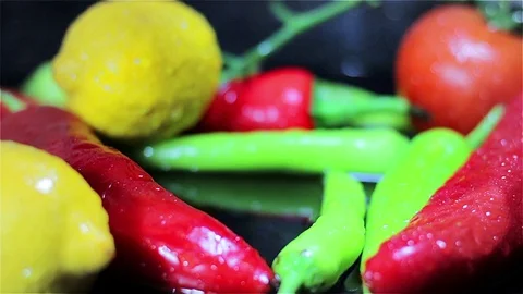 Slowmotion Tomatoes falling into fresh vegetables on black surface Stock Footage 73605244