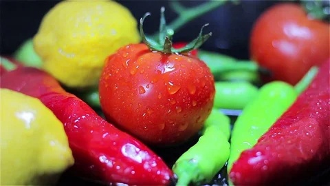 Slowmotion Tomatoes falling into fresh vegetables on black surface Video stock 73605318