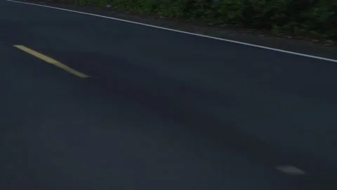 Slowmotion tracking shot looking down on dotted yellow lines on dark pavement Stock Footage 220312875