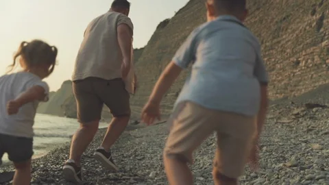 A slowmotion of two kids playfully chasing their father Stock Footage 122429168