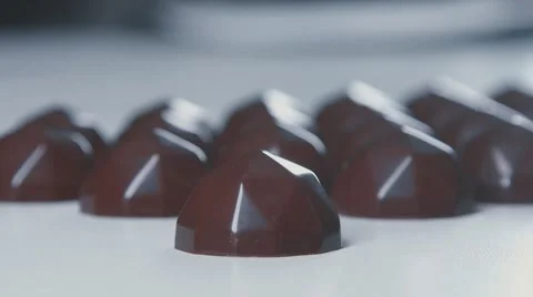 Slowmotion. Unknown cuts chocolates using large kitchen knife Video stock 69054650