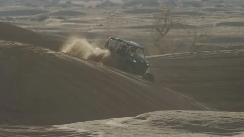 Slowmotion of UTV playing in red sand dunes at sunset in Utah desert Stock Footage 234035760