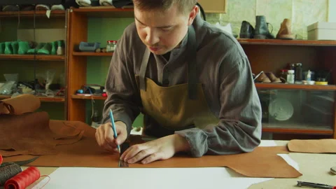 Slowmotion video. A young tanner makes marks with a pencil and ruler on a piece Stock Footage 143720424