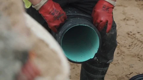 Slowmotion woker in red gloves pull string arond plastic pipe between his legs Stock Footage 75239163