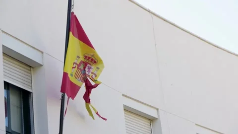 Slowmotion a worn Spanish flag waves from a pole, frayed edges and torn fabric. Stock Footage 307571165