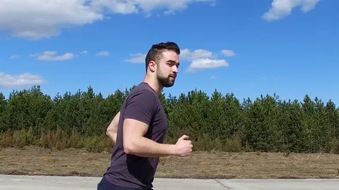 Slowmotion Young Man Running On Empty Runaway Road Side and Wink Stock Footage 105035708