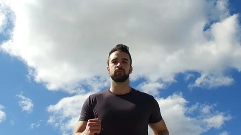 Slowmotion Young Man Running on Runaway Road Under Sky Low Angle Stock Footage 105018400