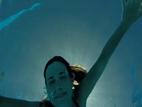 Slowmotion, young woman finding camera underwater, smiling Stock Footage 77683686