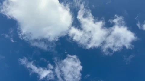 Slow‑moving white clouds drifting across a bright blue sky. Stock-Footage 337857999