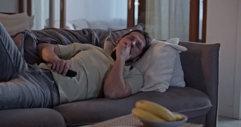 Sluggish man lying on sofa and using remote control Stock Footage 271159280