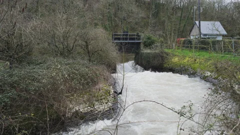 A sluice gate and weir create turbulent white water on a river. 4K locked tripod Stock Footage 142375063